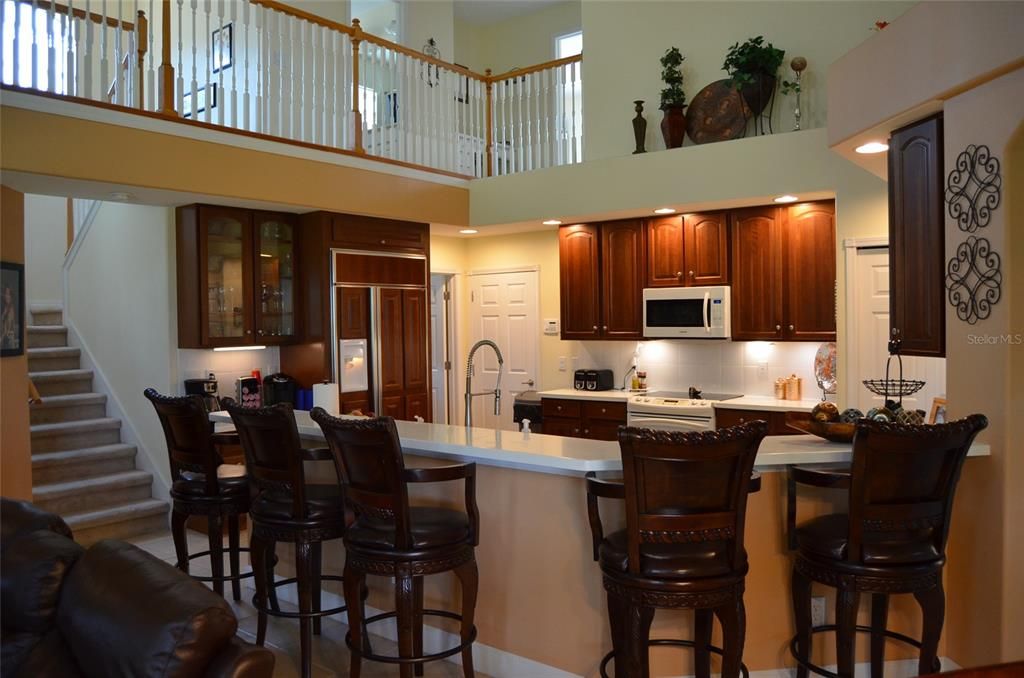 View of kitchen / breakfast bar from family room.  Stairs lead to 3 upstairs bedrooms.