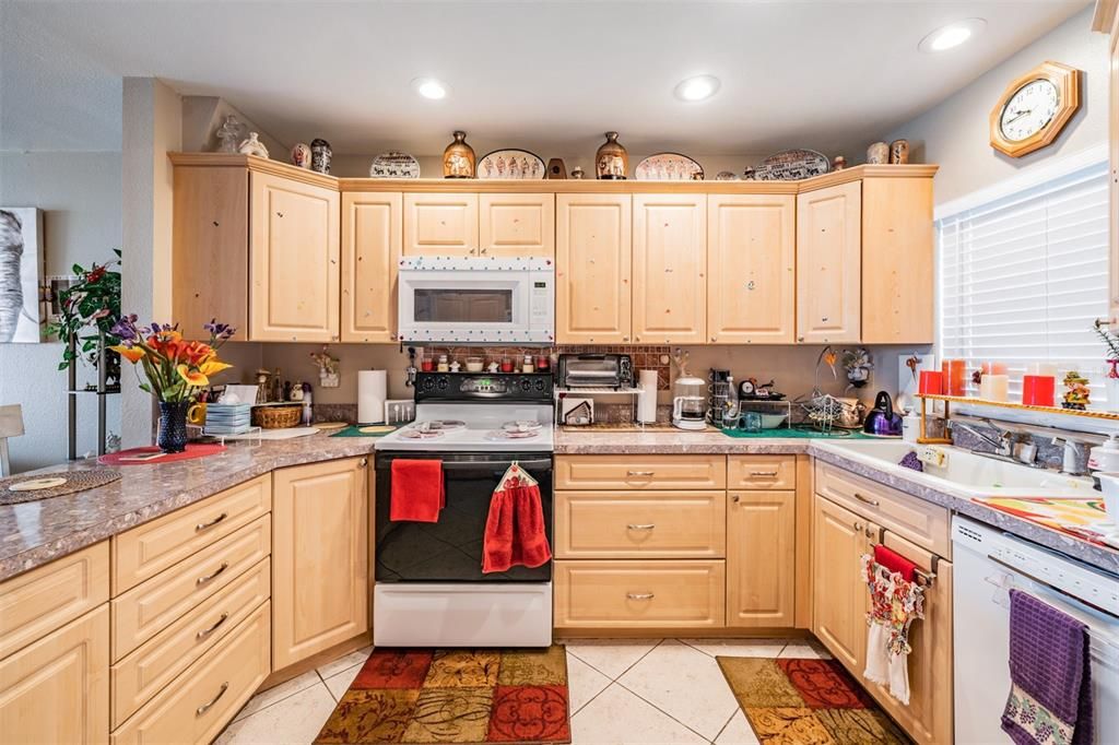 Renovated, expanded kitchen with extra cabinet space, drawers, built in microwave, eating countertop area, tile floors, and window over the sink.