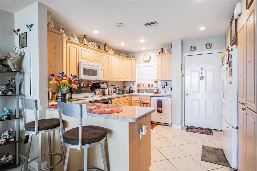 Renovated, expanded kitchen with extra cabinet space, drawers, built in microwave, eating countertop area, tile floors, and window over the sink.