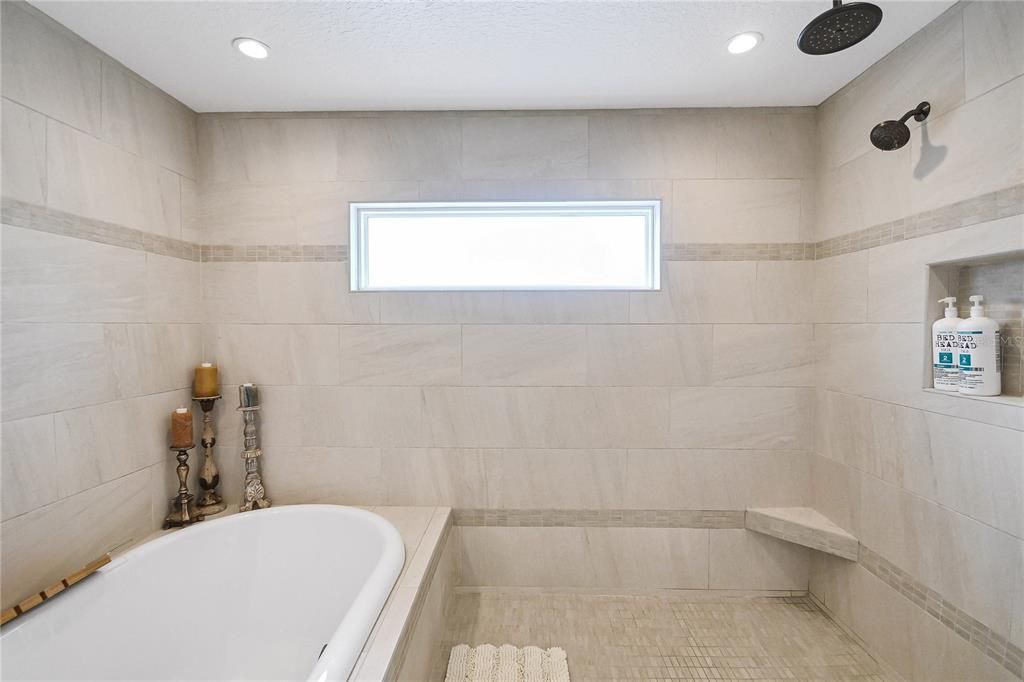 Walk-in shower with three faucets and soaker tub.