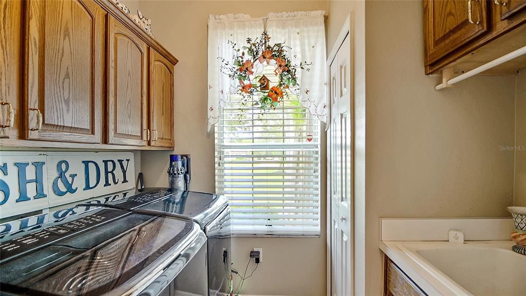 Laundry room has a nice sink with hanging rack above.  Upper cabinets and an additional closet allow for plenty of storage.