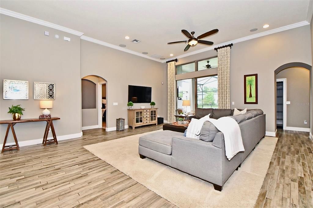 Enjoy relaxing in the large great room with surround sound speakers, crown molding, and gorgeous flooring while also over looking the tranquil pool and spa area!