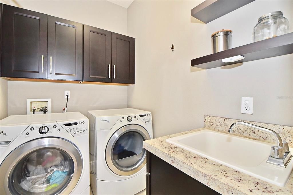 Spacious laundry room with sink & wood cabinetry.