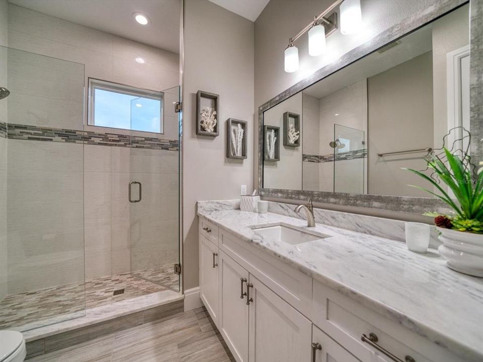 Luxurious Guest bath with custom wood cabinetry, porcelain flooring.