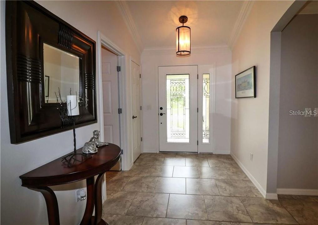 Foyer with crown molding and tile floor