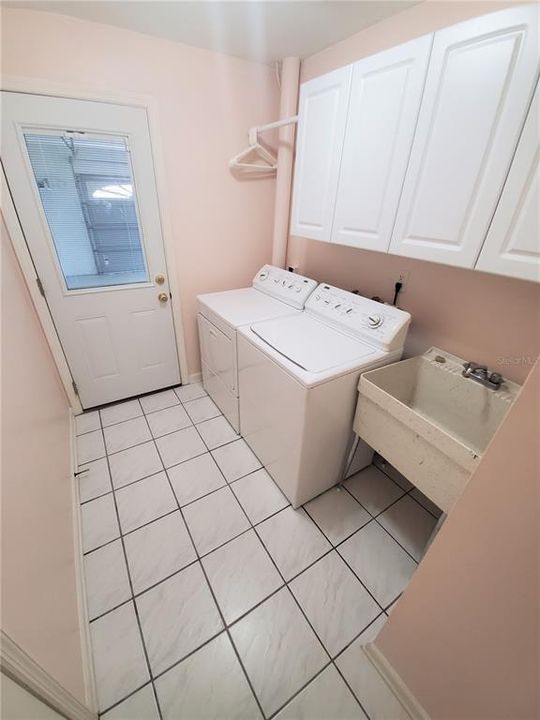 Inside Laundry Room, with utility sinks & cabinets and door to garage