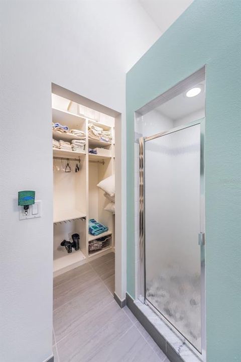 Walk-in shower and large closet with built-in shelves