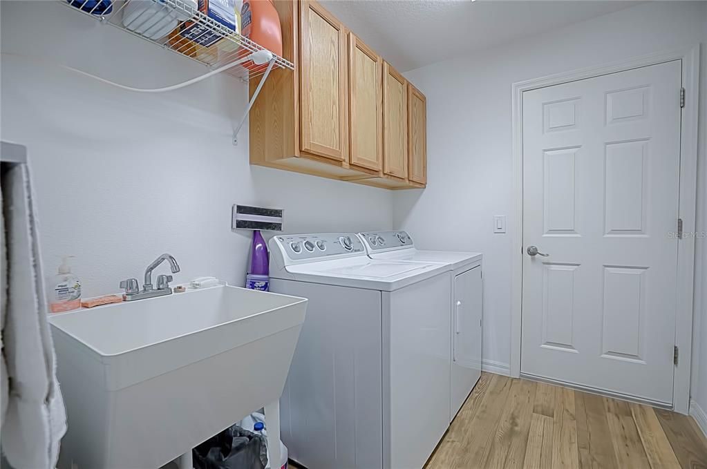 INSIDE LAUNDRY ROOM WITH EXTRA CABINETS AND A SINK!  THE DOOR THAT LEADS TO THE GARAGE HAS A RETRACTABLE SCREEN DOOR TOO!