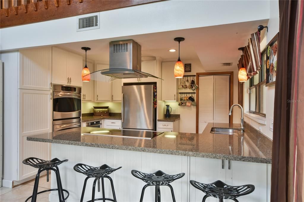 eat in bar area with range top and looking into kitchen and door to laundry