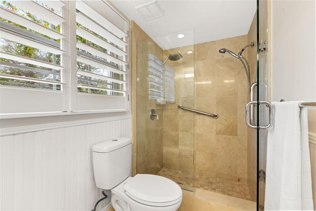 First floor primary bathroom walk in shower with plantation shutters