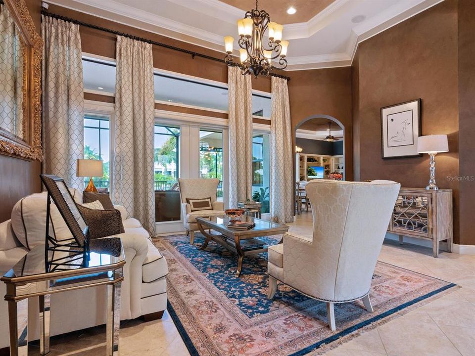 Open formal living room offering a tray ceiling, 17' ceiling and French doors to the lanai.