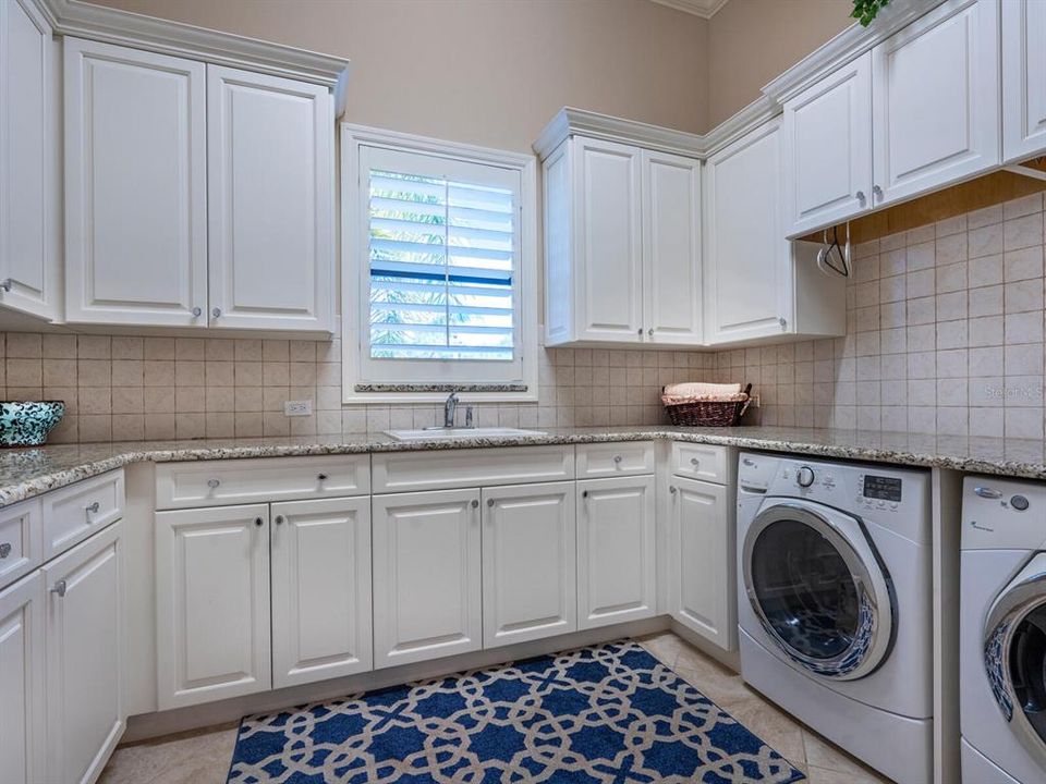 Large laundry room with utility sink and plentiful storage.