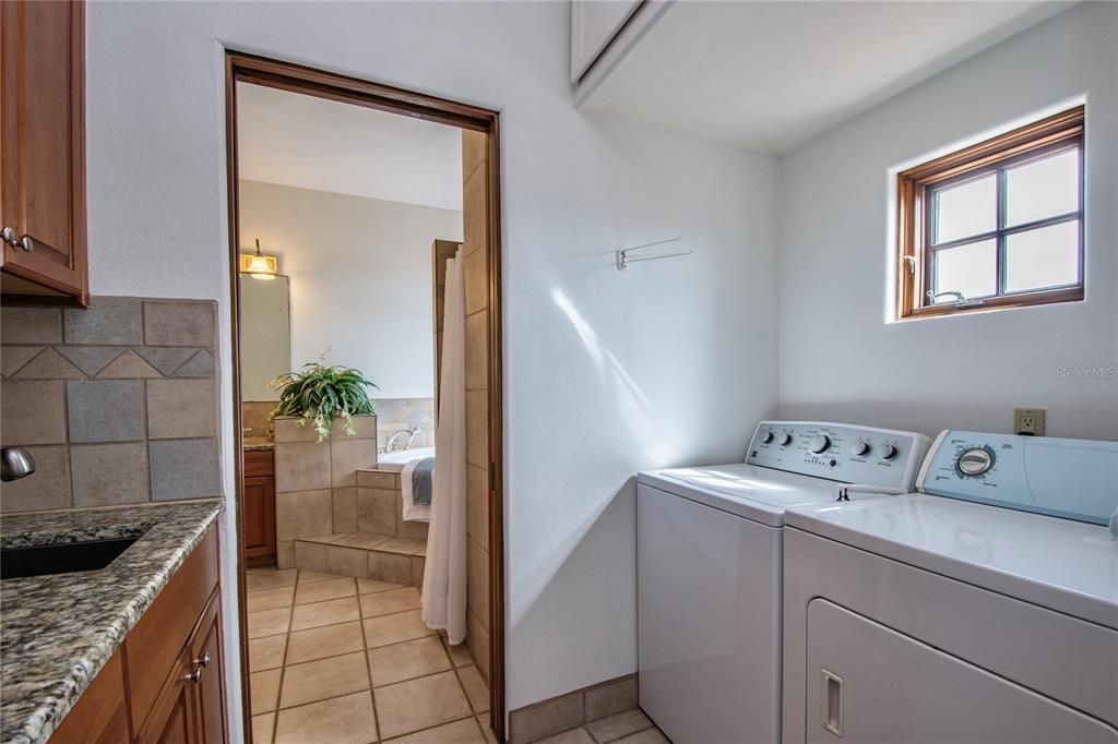 Large Laundry room with a window is well positioned adjacent to the Master Bathroom and has plenty of storage in solid wood cabinetry with granite countertops & even a utility sink.