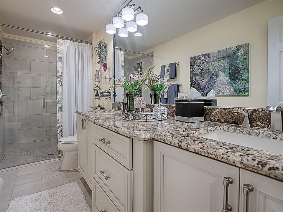 BEAUTIFUL REMODELED MASTER BATHROOM WITH LARGE TILE FLOORING, GRANITE COUNTERTOPS, FRAMELESS GLASS SHOWER DOOR AND LOVELY TILE WORK IN SHOWER! NOTICE THE LIGHT FIXTURES ARE MOUNTED TO THE MIRROR!