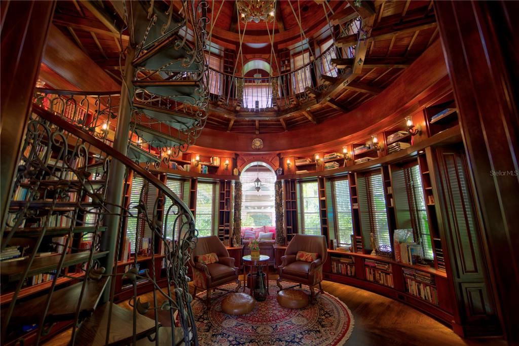 The first floor of the elegant two story library.  The custom built spiral stair case provides access to the second floor.    The carvings in the columns feature master literary works.