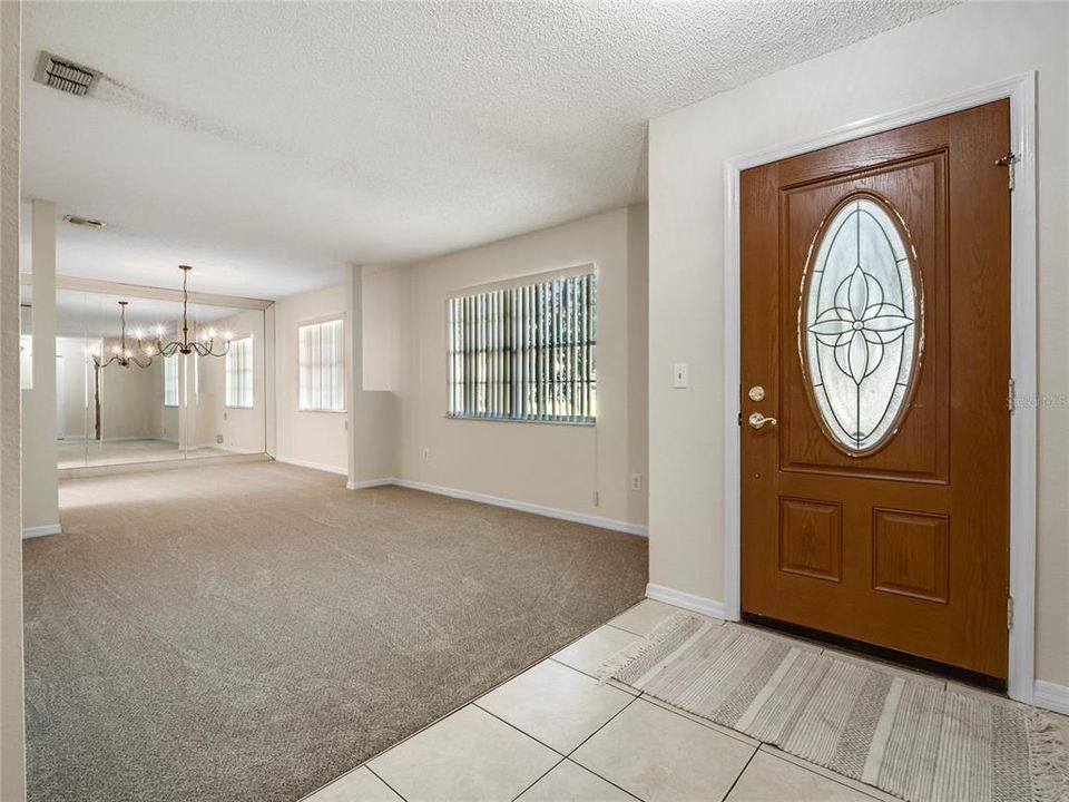As you enter the front door, you are greeted by a large formal living and dining area