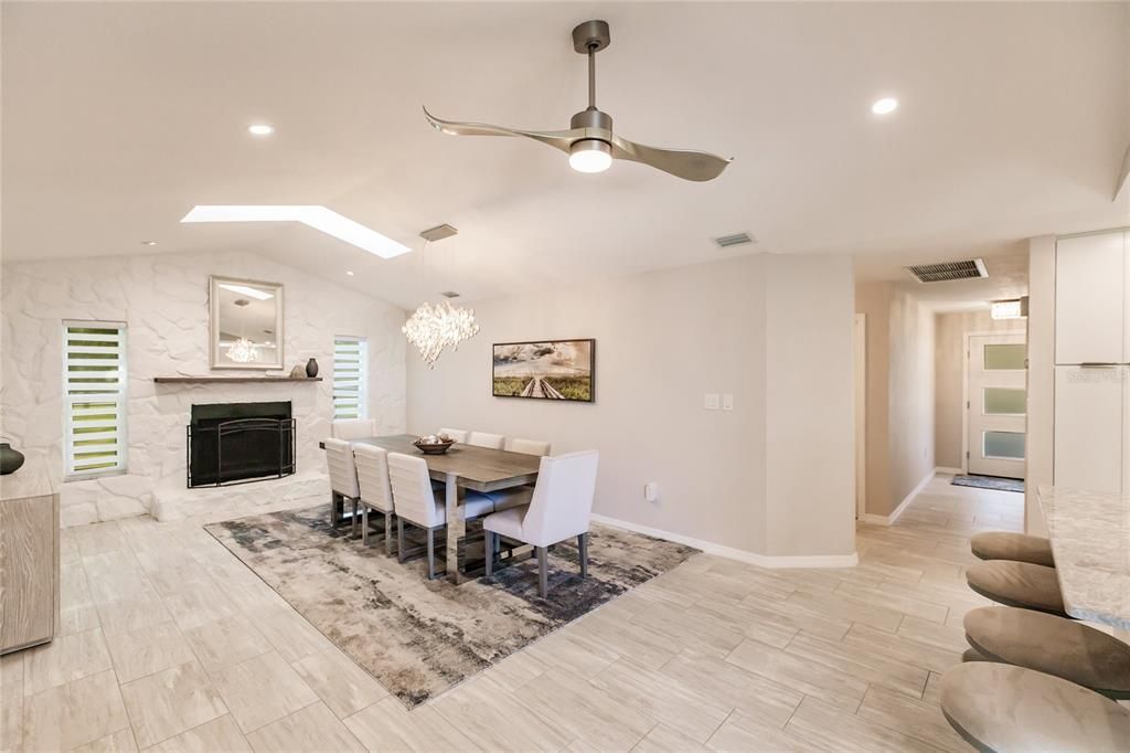 THE DINING ROOM WHICH FEATURES VAULTED CEILINGS, GLASS SLIDERS TO THE LANAI, STONEWALL/WOOD BURNING FIREPLACE, WET BAR, AND MODERN CHANDELIE