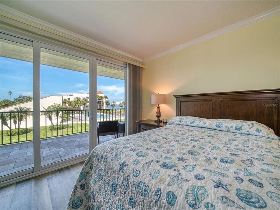 Large guest bedroom with crown molding and private patio access.