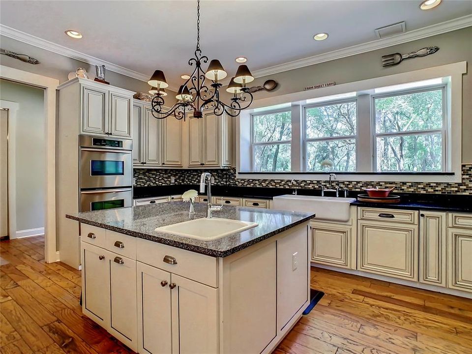 Large Island with veggie prep sink, Double Ovens, Apron Front Farm Sink and an elegant chandelier
