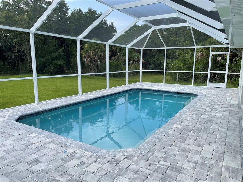 Custom paver patio and screened enclosure surrounds the beautifully tiles pool.