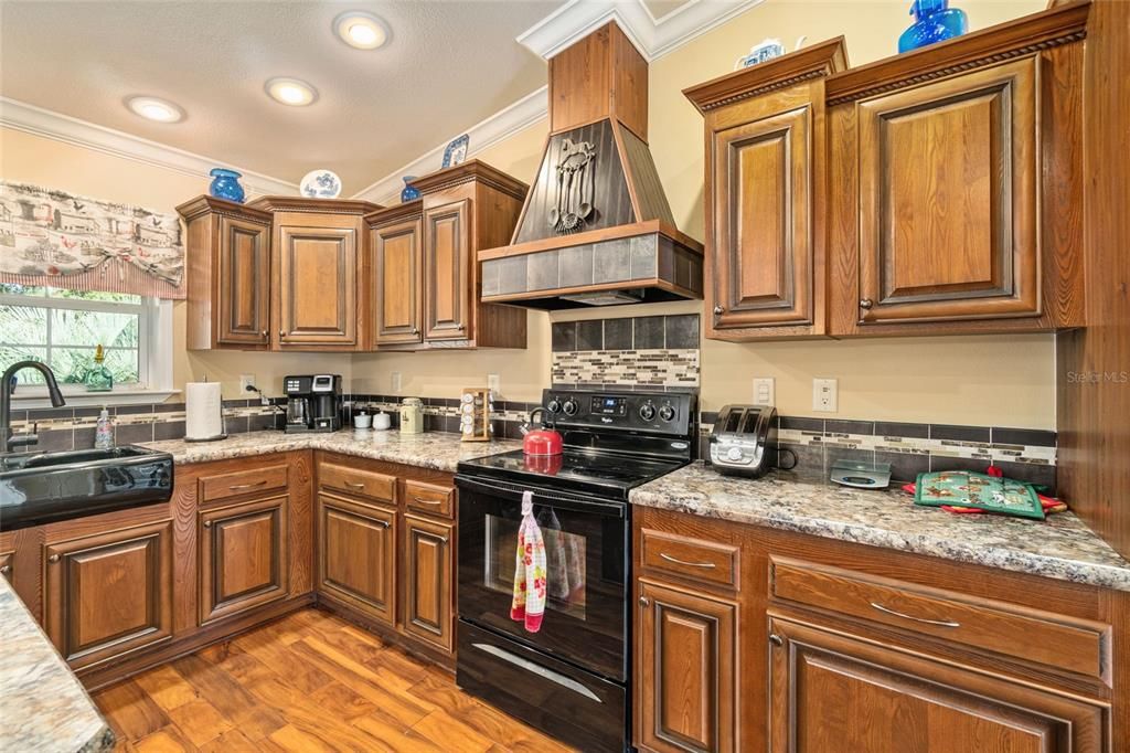 Staggered wood cabinetry with soft close drawers, lazy susan in cabinet, Black farm sink, tiled back splash, pretty hood