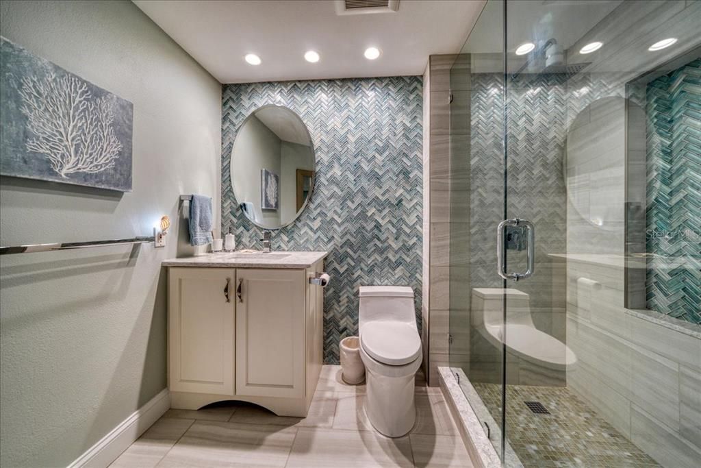 The hall/guest bath is just stunning! Check out the unique glass tile work and the gorgeous glass shower doors and the shower niche!