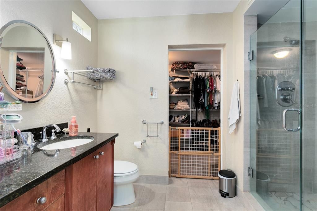 An UPDATED en suite master bath includes a GRANITE topped vanity, frameless glass enclosed walk-in shower and a walk-in closet.