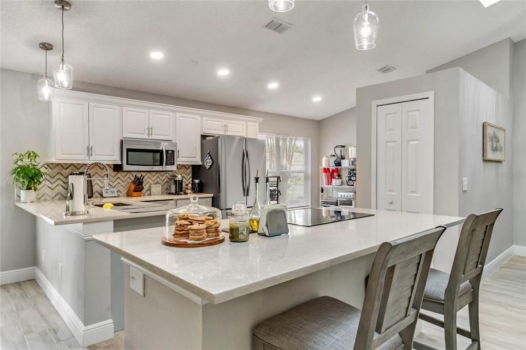The highly desired OPEN KITCHEN LAYOUT showcases the gorgeously renovated features to include a GRANITE TOP ISLAND/BREAKFAST BAR with a BUILT-IN COOKTOP and glistening PENDANT LIGHTS!
