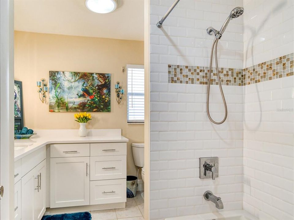 Bathroom for additional bedrooms with tub/shower and subway tile with beachy themed inlaid mosaics.