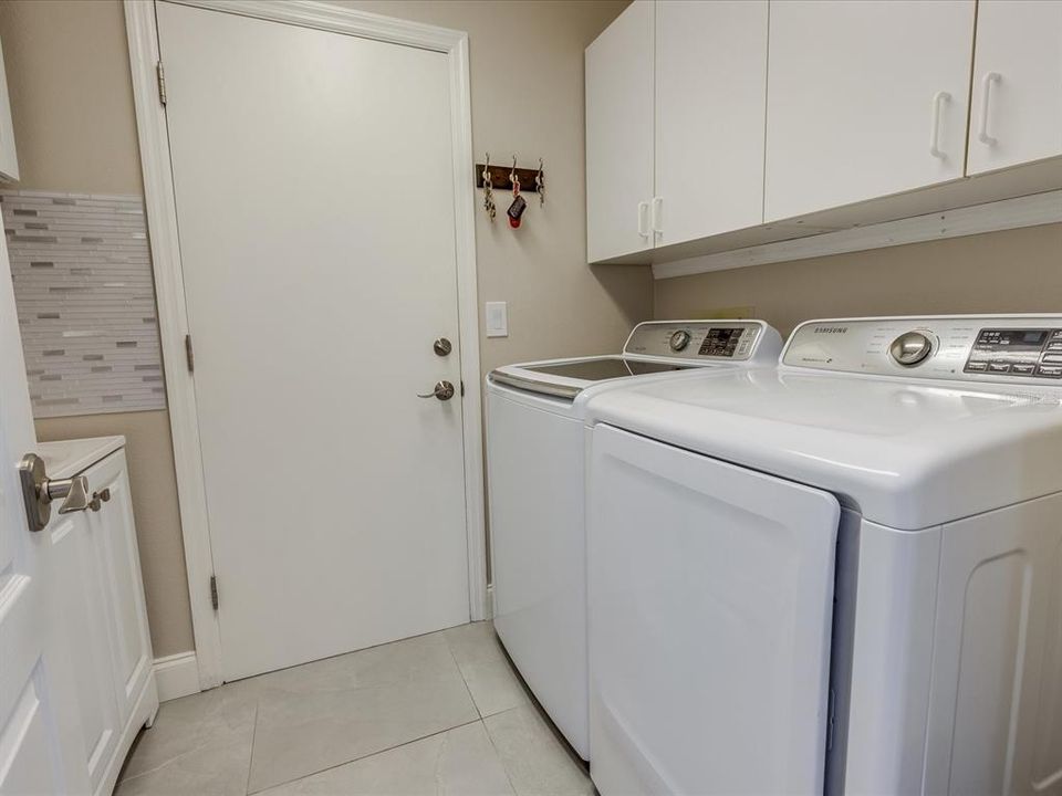 Indoor laundry. Additional storage cabinets across from washer/dryer.