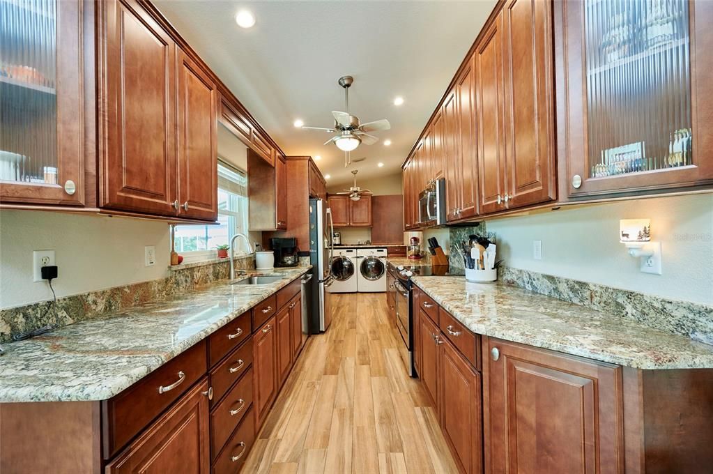 Galley-style kitchen with gorgeous cabinetry, loads of granite countertops.  Washer & dryer area are located at the end of the kitchen.