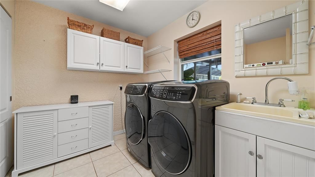 Huge indoor laundry room with lots of storage, washer, dryer and fridge convey.