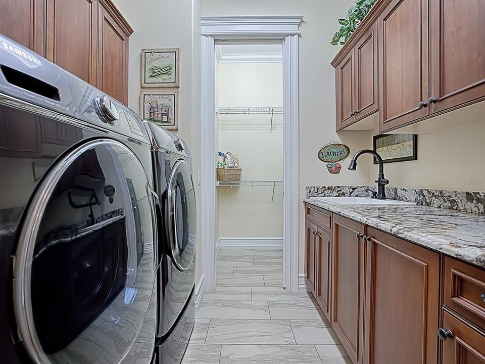 PLENTY OF CABINET SPACE GALORE IN THIS LAUNDRY ROOM WITH SINK ANS PULL-OUT LAUNDRY BASKETS BUILT RIGHT IN! NOTICE THE OVERSIZED STEAM WASHER AND DRYER UNITS