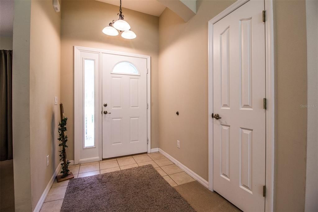 Tiled foyer and coat closet open to...