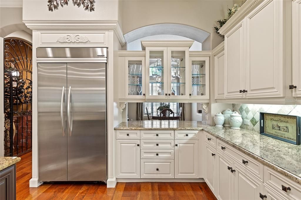 Gleaming Stainless Steel Refrigerator is a dramatic focal point along with the glass doors and custom cabinetry.
