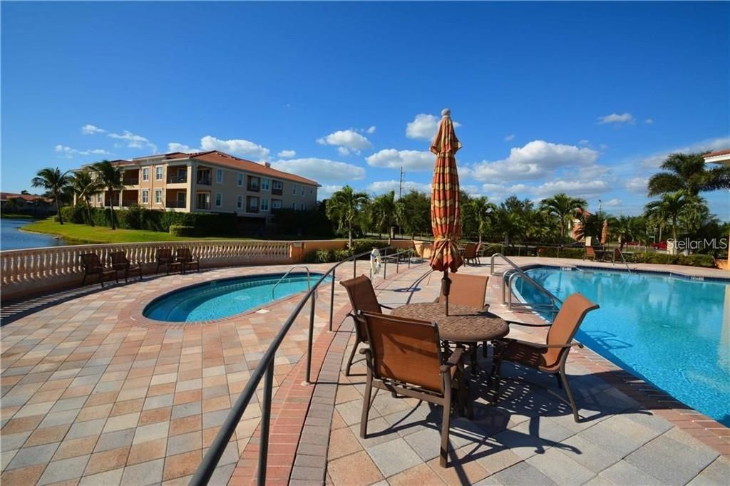 The heated community pool & hot tub is surrounded by pavers.