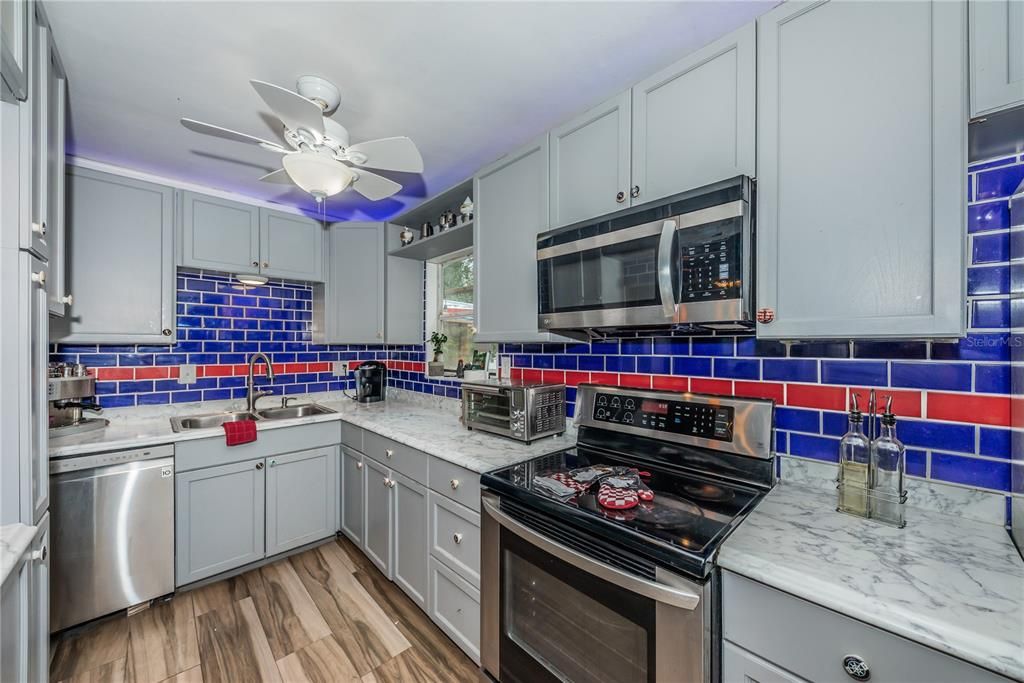 kitchen has subway tile, newer cabinets and formica countertops, flooring is porcelain tile