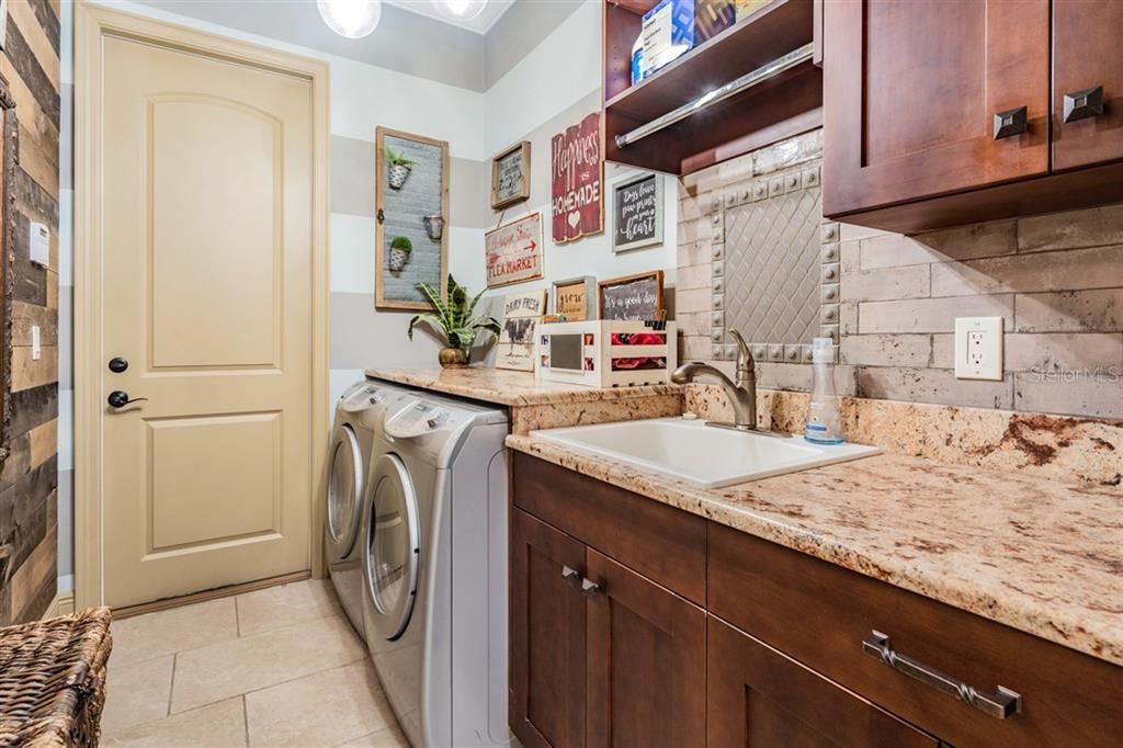 Walk in laundry room with extensive built ins, utility sink and granite countertops