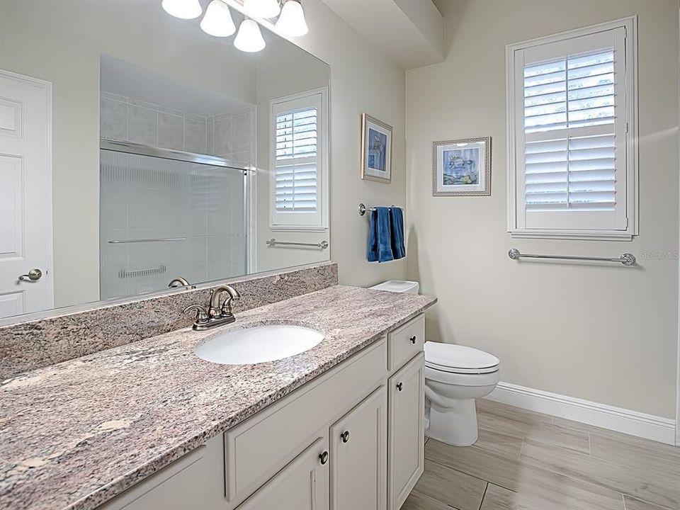 GUEST BATH BETWEEN THE 2 GUEST ROOMS HAS A LINEN CLOSET, WOOD LOOK PORCELAIN TILE FLOORING, GRANITE COUNTER TOPS AND PLANTATION SHUTTERS!