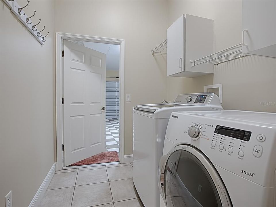 LAUNDRY ROOM WITH CABINETS AND SINK!  SAMSUNG WASHER AND DRYER DO REMAIN WITH THE HOME! STEP OUT INTO THE GARAGE FROM HERE!