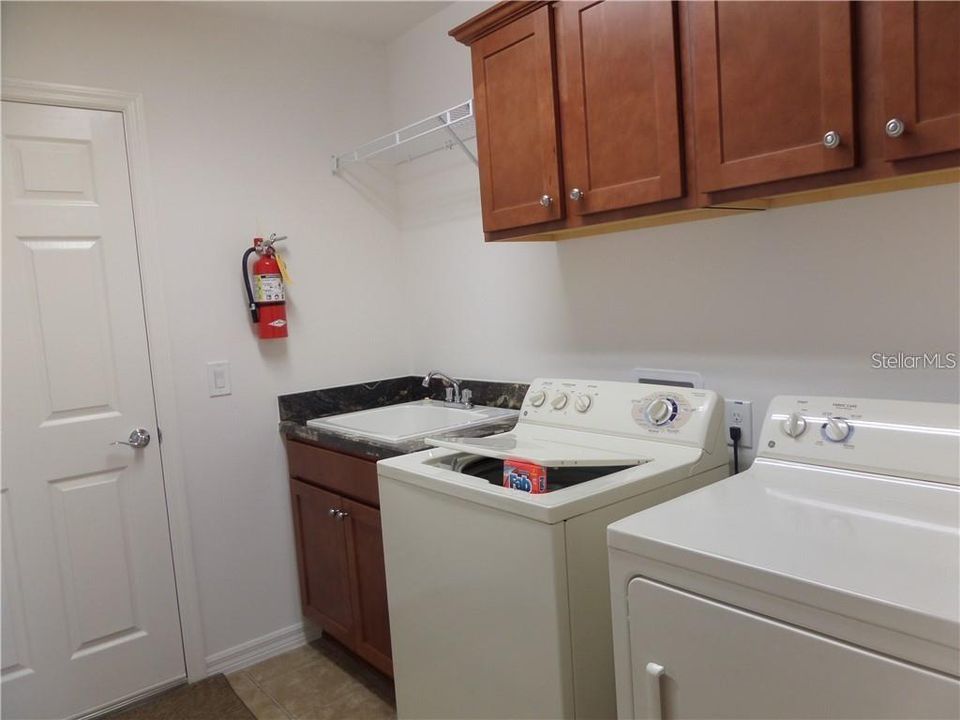 Laundry Room with washer, dryer, laundry sink and cabinetry leading to the garage