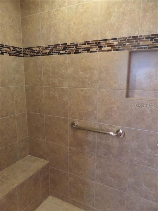 Master Bathroom shower with ceramic tile and shower bench and shampoo niche