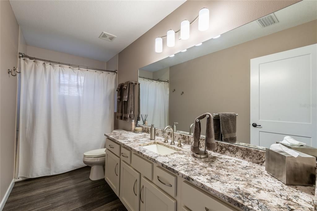 Guest bathroom with tub / shower combo, granite and access accross hall to pool