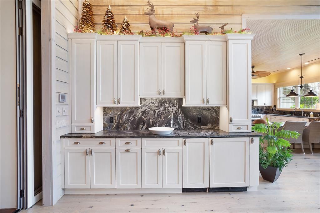 Another part of the outdoor kitchen includes a beverage fridge, granite & another sink.