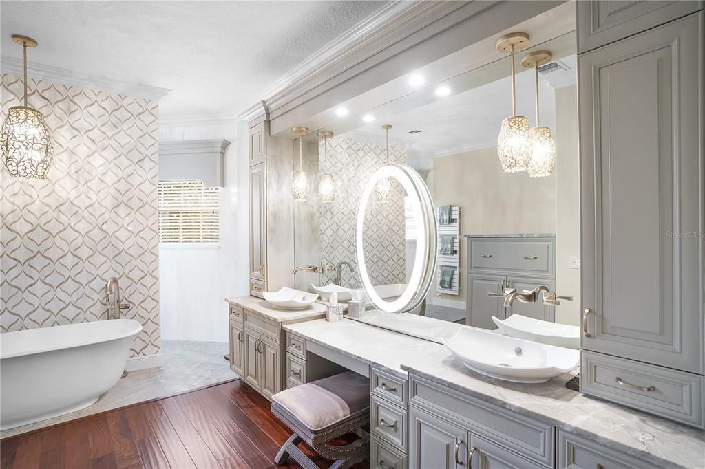 The vanity is beautifully lit with floating faucets & a lit center mirror.
