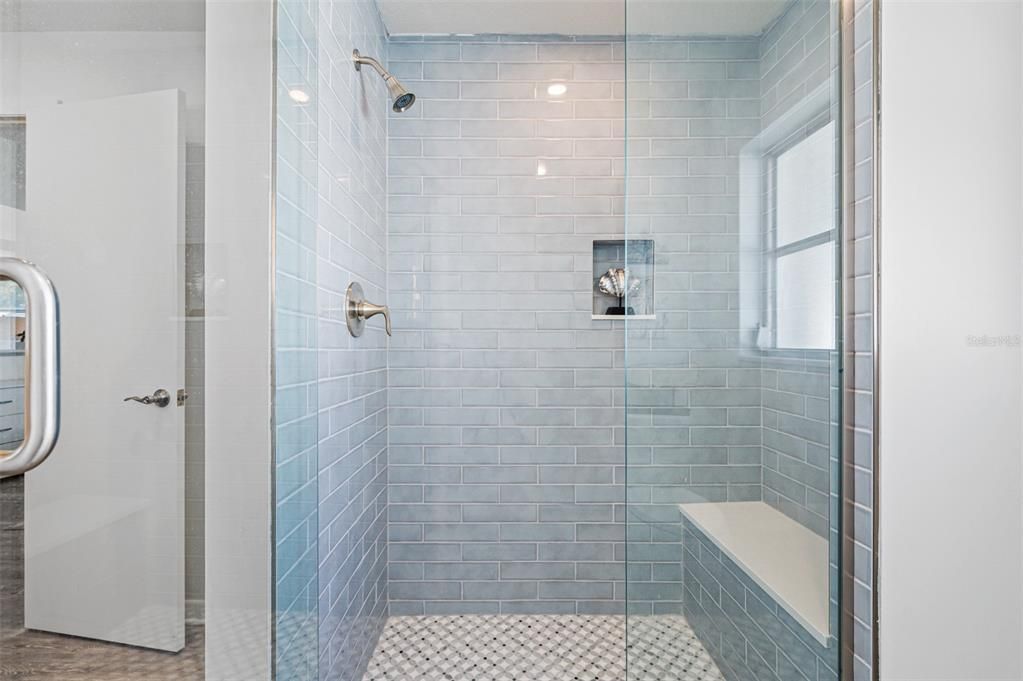 marble tile floors and a shower seat / bench