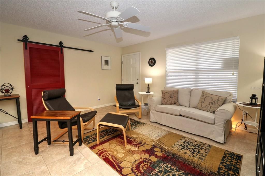 Living room has tile flooring and the pretty red ban door that separates the guest bedrooms into a suite.