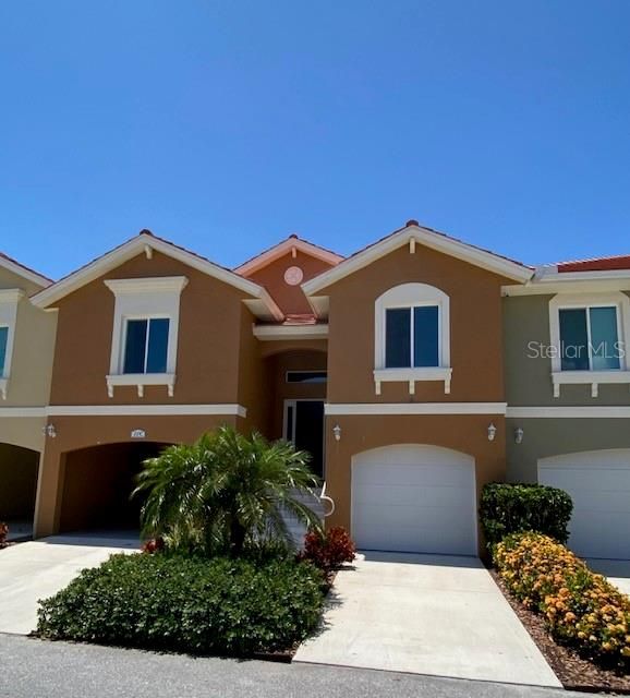 Front elevation showing first level Garage, carport parking on the left and tropical, mature landscaping.