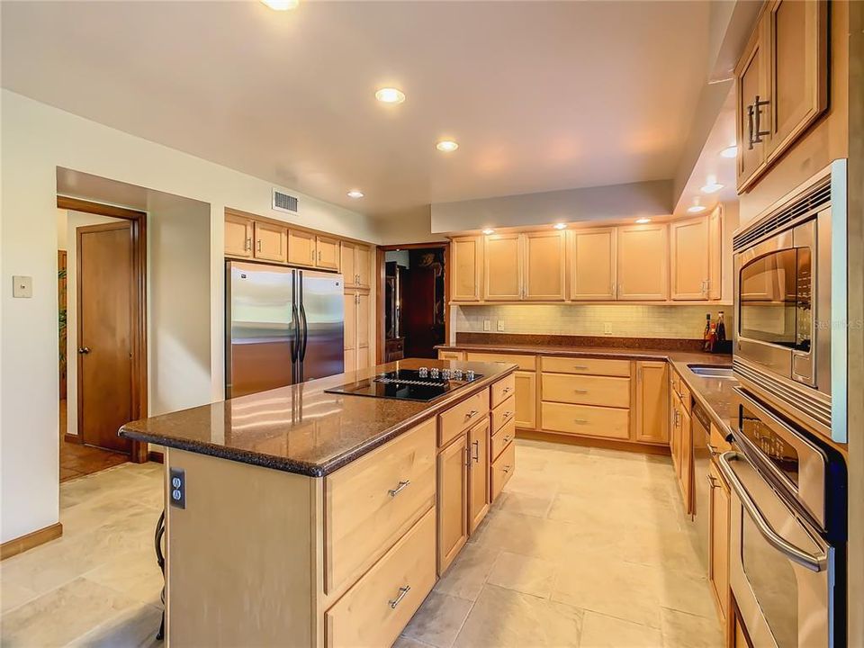 The cooktop located on the island/breakfast bar is a main feature in this kitchen.  The chef loves for the family to be close by while cooking the next dinner sensation.  The pantry is located to the right of the refrigerator/freezer and has pull out drawers.