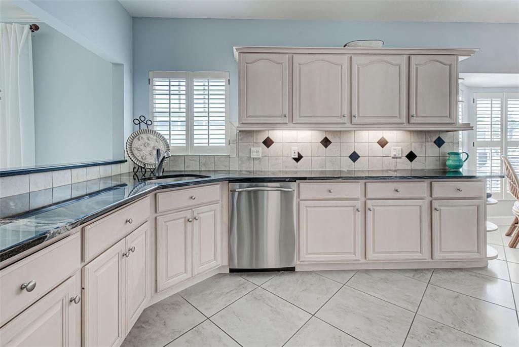 Wonderful kitchen features gleaming granite countertops, wood cabinets, classy backsplash and even pullouts.